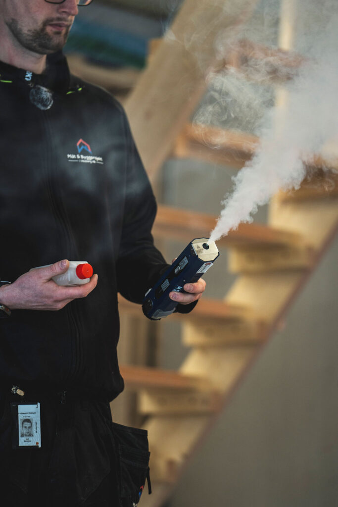 Byggnadsingenjör kontrollerar rökflöde under tätighetsprovning i Örebro